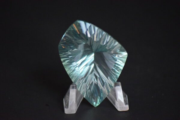 A large green crystal sitting on top of a stand.