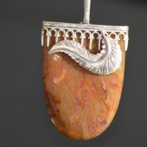 A silver and stone pendant hanging from a metal rod.