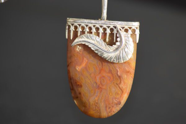 A silver and stone pendant hanging from a metal rod.