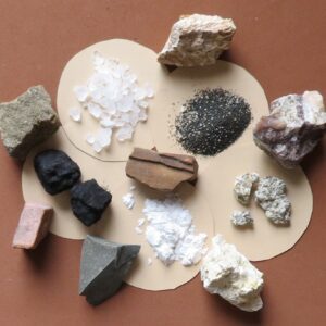 A variety of rocks and minerals are arranged on paper.