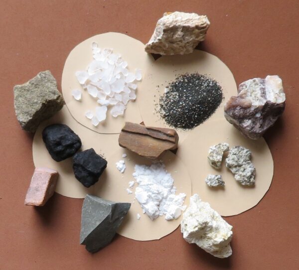 A variety of rocks and minerals are arranged on paper.