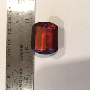 A red and blue glass bead is next to a ruler.