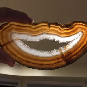 A person holding an agate slice with a smile on it.